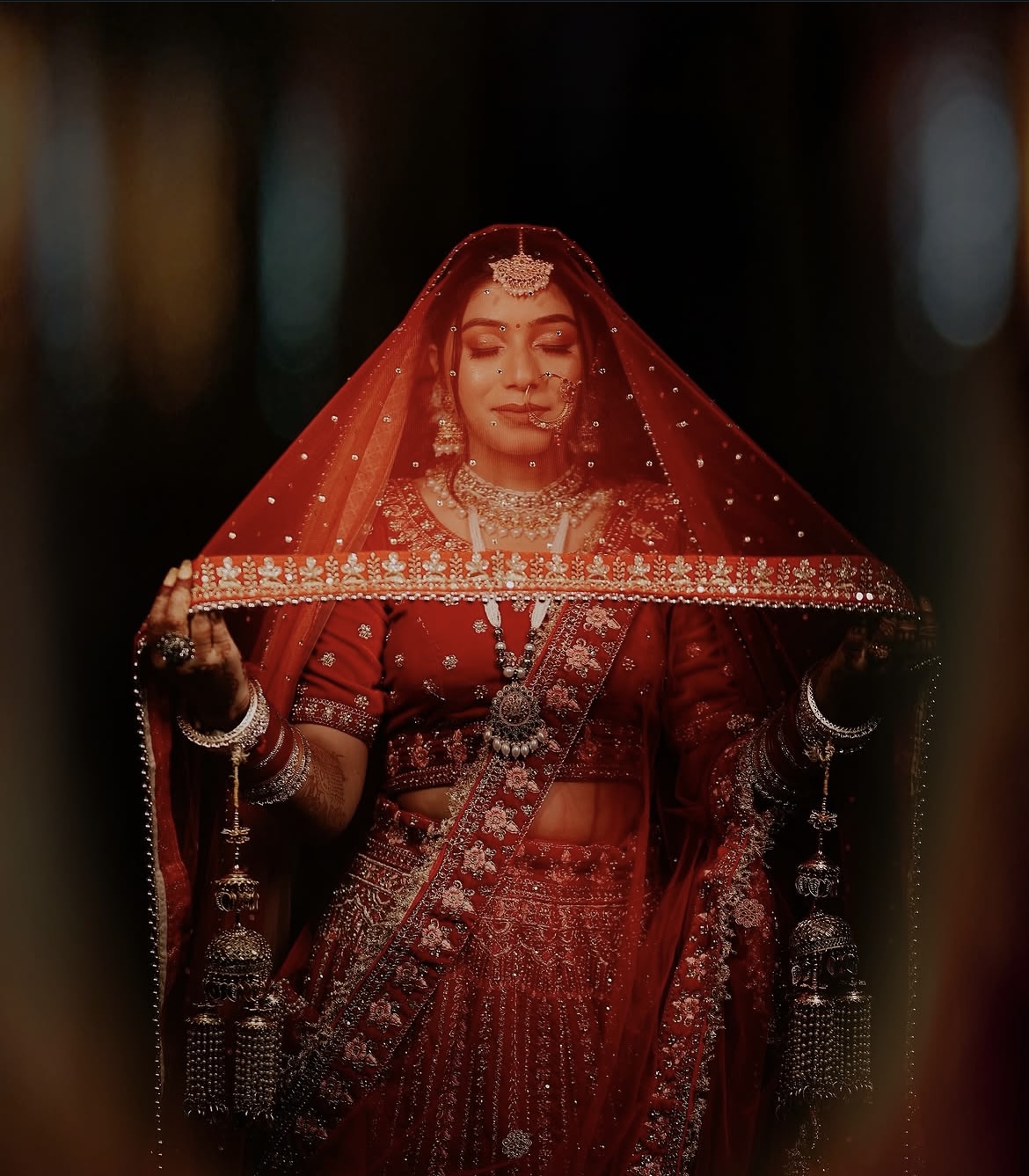 Bride in a red wedding outfit holding her veil